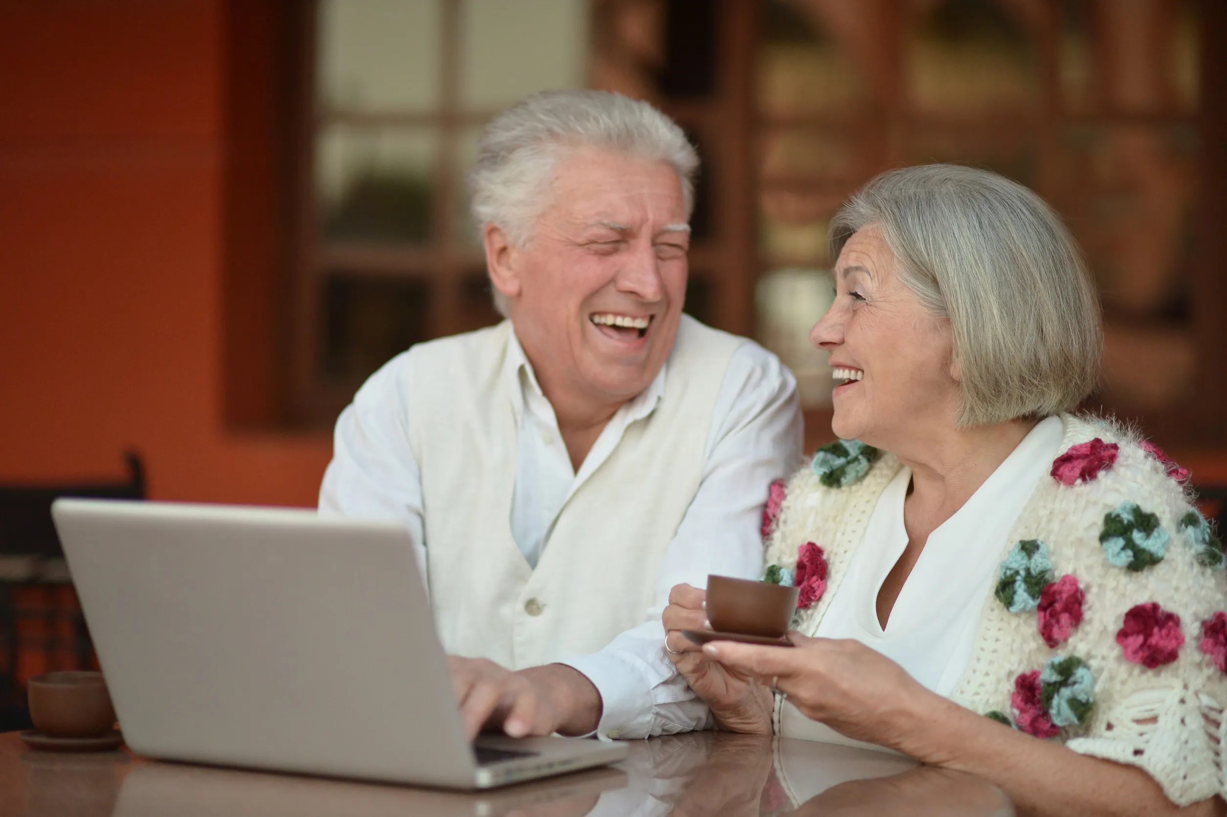 Mature couple sitting with laptop and coffee in hotel Mature couple sitting with laptop and coffee in hotel